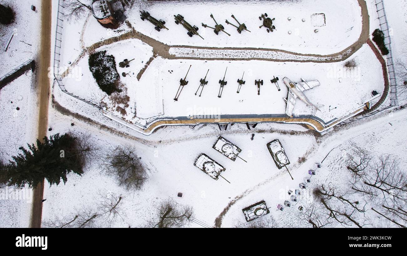 Aerial view of snow-clad tanks, artillery, and a jet fighter in Poznań Citadel during winter, shot by drone. Stock Photo