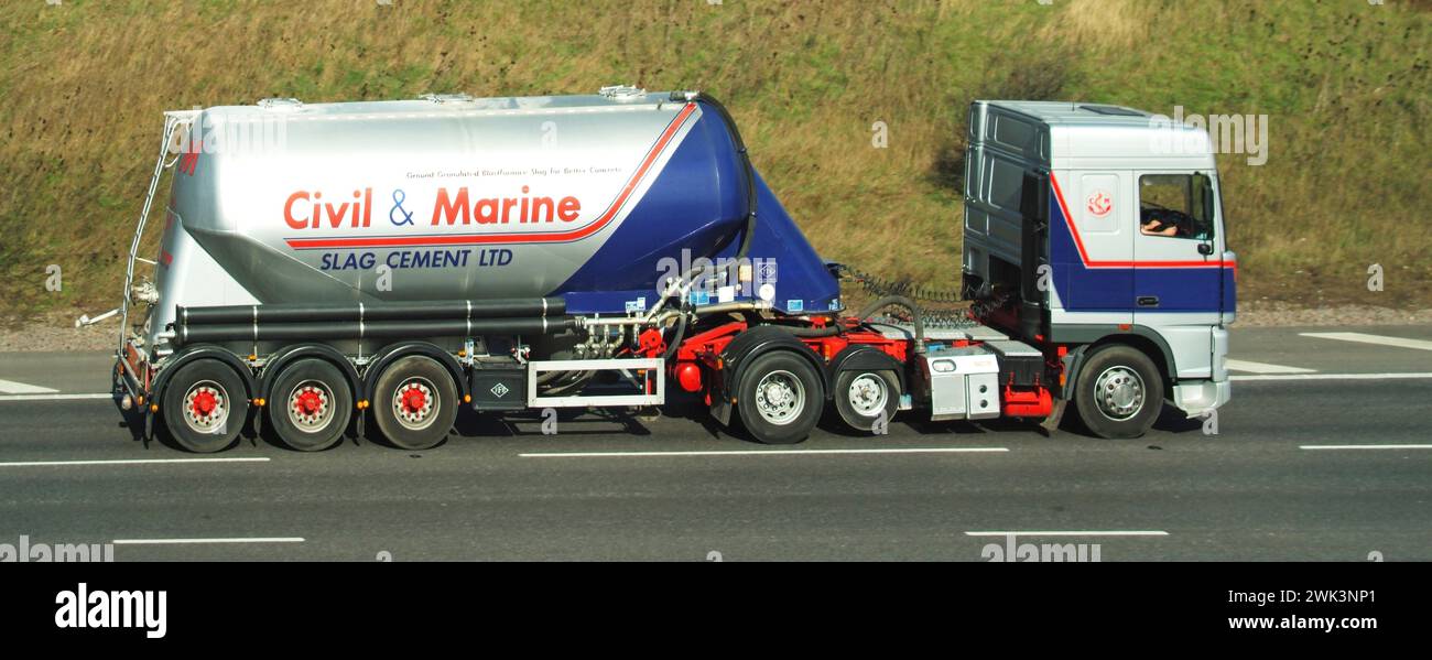 Civil & Marine Slag Cement business logo brand on historical archive view of a hgv lorry articulated tanker semi-trailer truck combination vehicle with raised economy axle driver at work driving along M25 motorway road London orbital route on Essex section England UK Stock Photo