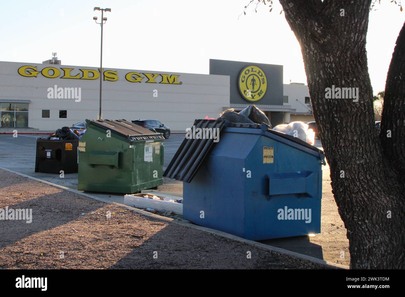 An overflowing commercial dumpster in the parking lot of a Gold's Gym location in San Antonio, Texas, USA, on February 18, 2024. The first location of a Gold's Gym was in Venice Beach, California. Today locations are worldwide. In 2020, the gym was acquired by Rainer Schaller's RSG Group GmbH. GmbH also owns the European McFit fitness chain. (Photo by Carlos Kosienski/Sipa USA) Stock Photo