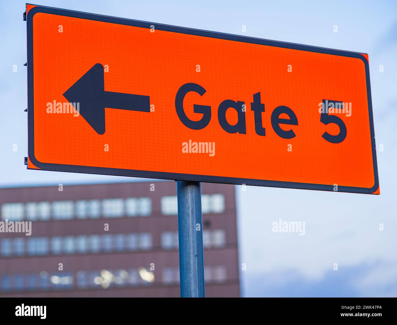 This image captures a vibrant orange sign featuring a arrow pointing