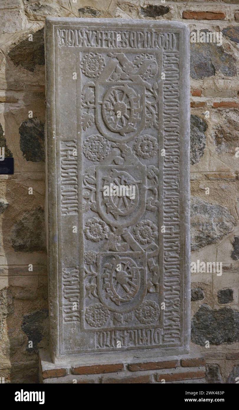 Tombstone of Diego de Santa Catalina. Vegetal decoration. In the central part, shields depicting the 'Catherine Wheel', instrument with which St. Catherine (Santa Catalina) was executed by order of Emperor Maximian. Inscriptions in capital Gothic characters in the border. Stone. 14th century. From the Church of San Román. Toledo, Spain. Museum of Visigoth Councils and Culture. Toledo, Castile-La Mancha, Spain. Stock Photo