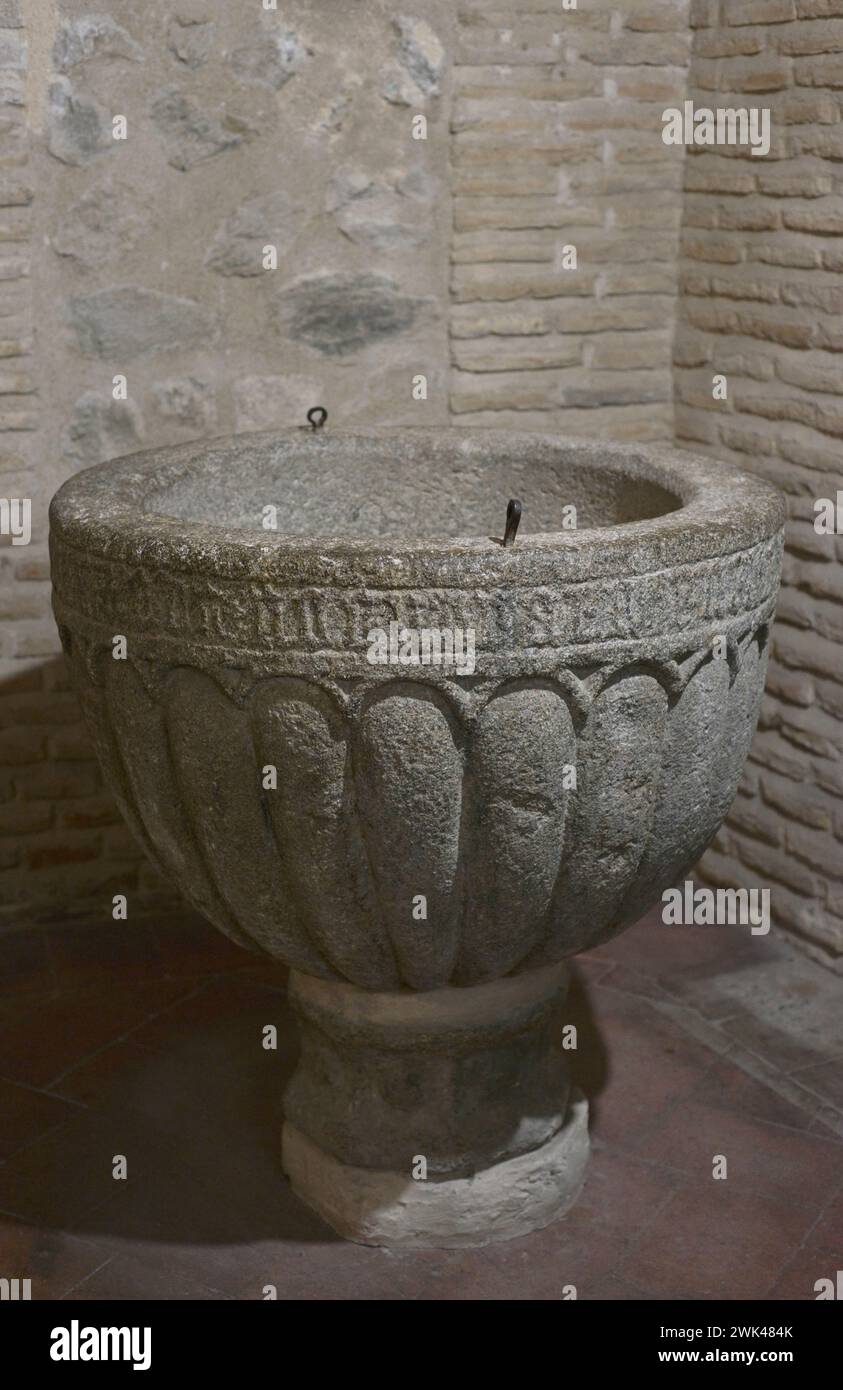Baptismal font decorated with gadroons under arches. Inscription in Gothic characters around the rim. Sandstone. 15th century. From the Church of San Román, Toledo, Spain. Museum of Visigoth Councils and Culture. Toledo, Castile-La Mancha, Spain. Stock Photo