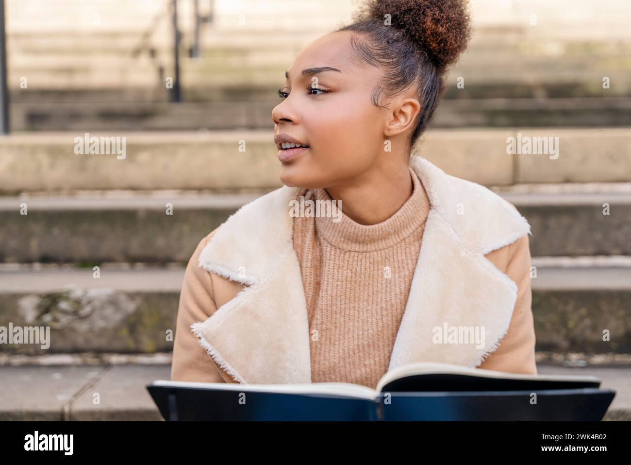Portrait of beautiful young african american woman student sitting at a ...