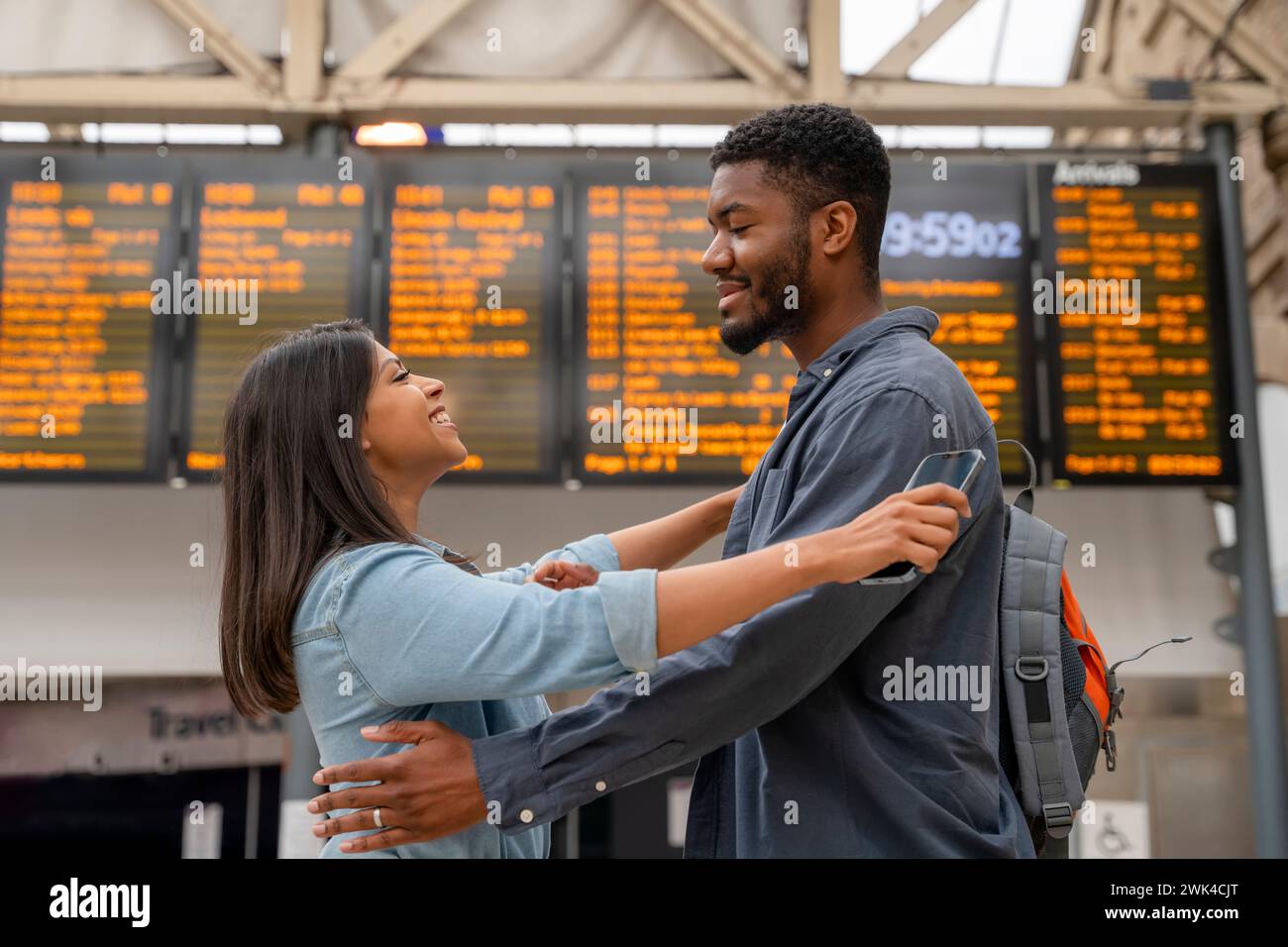 Happy man and woman in love meet and cuddle at a train station in front ...