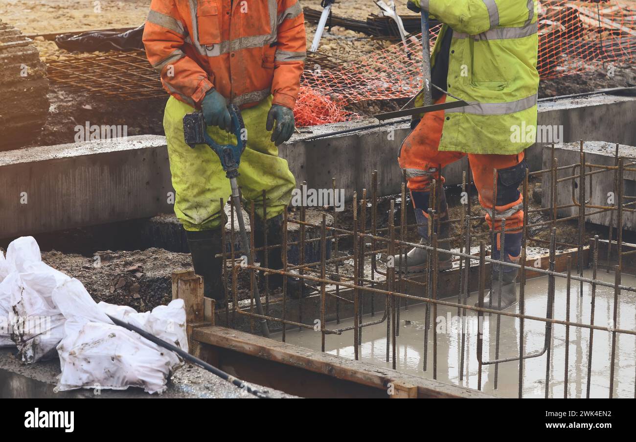 Concrete cast-in-place work. Builder level wet concrete. Concrete works on buildiiing construction site Stock Photo