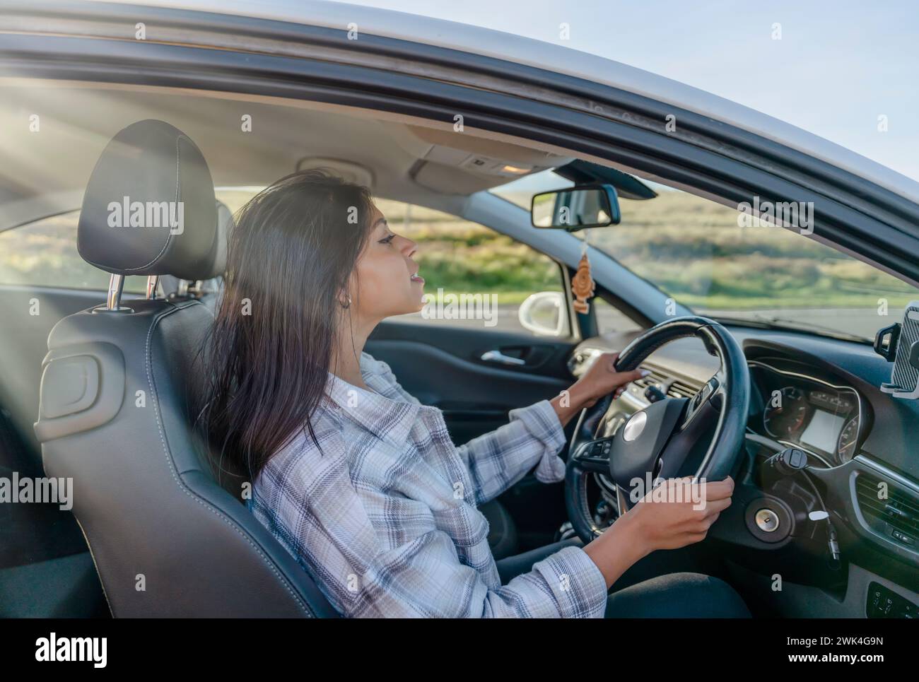 Portrait of a young woman sitting in a car and  holding on to the steering wheel. Buy your first car concept Stock Photo