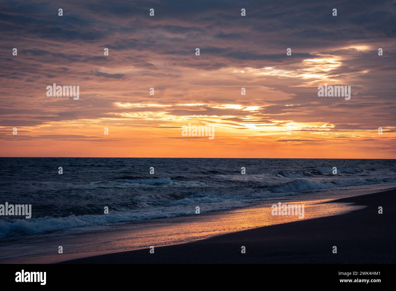 Wet surfline of black beach landscape photo. Beautiful nature scenery photography with bright sky on background. Idyllic sunset scene. High quality pi Stock Photo