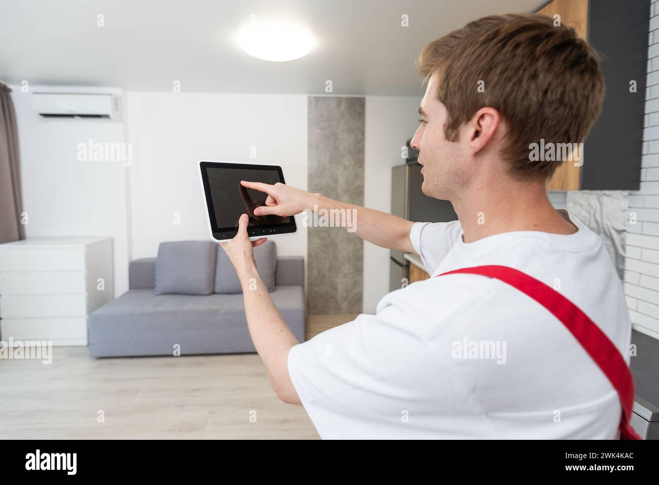 Worker with tablet computer checking alarm system indoors. Stock Photo