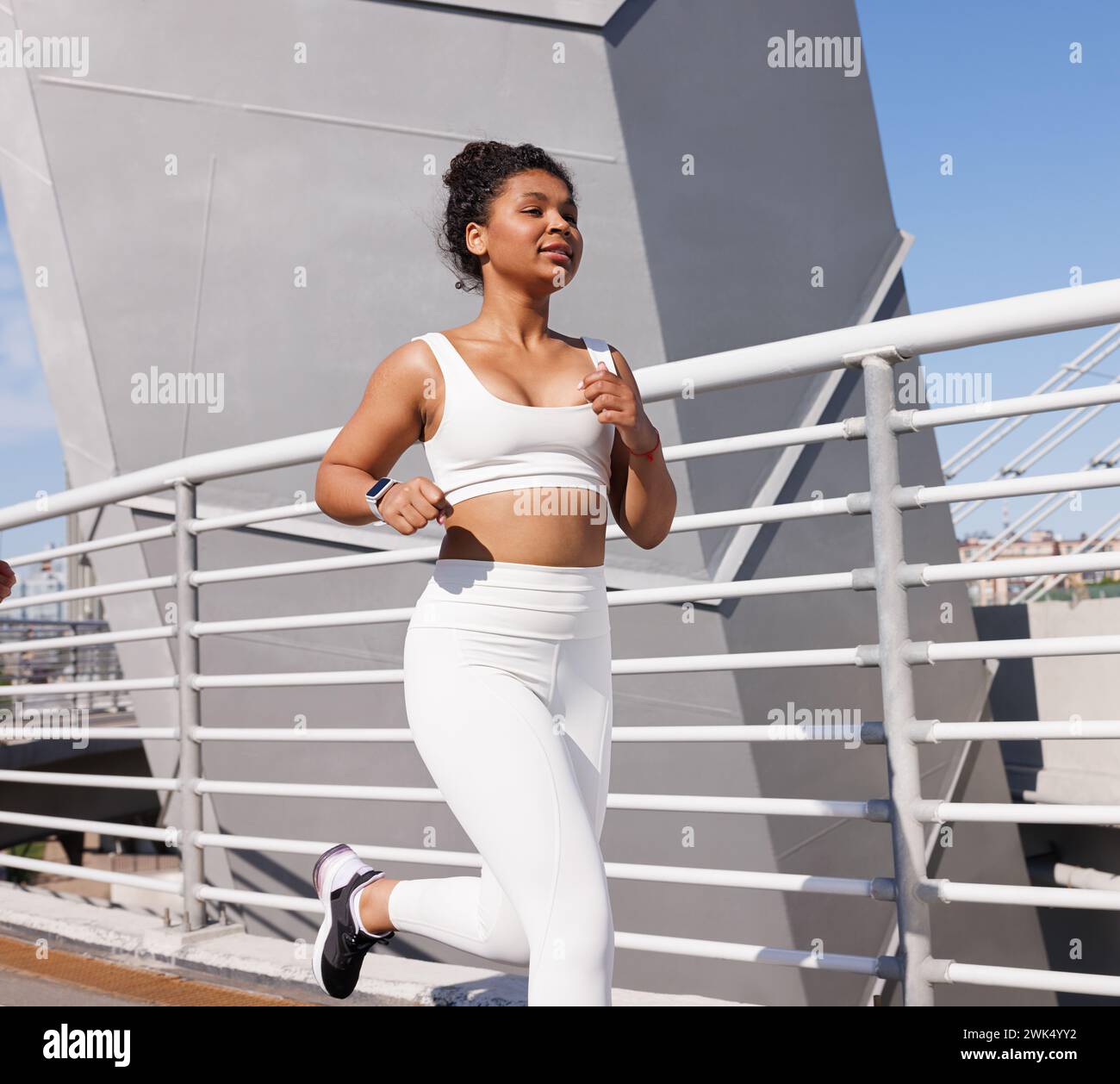 https://c8.alamy.com/comp/2WK4YY2/young-woman-in-white-sportswear-running-outdoors-on-bridge-female-in-white-fitness-attire-jogging-during-a-sunny-day-2WK4YY2.jpg
