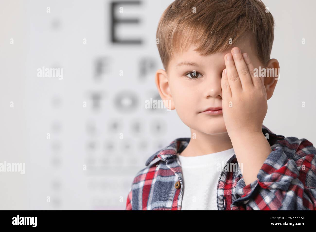 Little boy covering her eye against vision test chart Stock Photo - Alamy