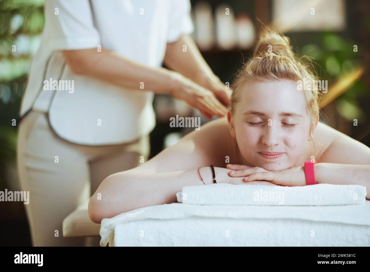 Healthcare time. female massage therapist in massage with teenage client making massage