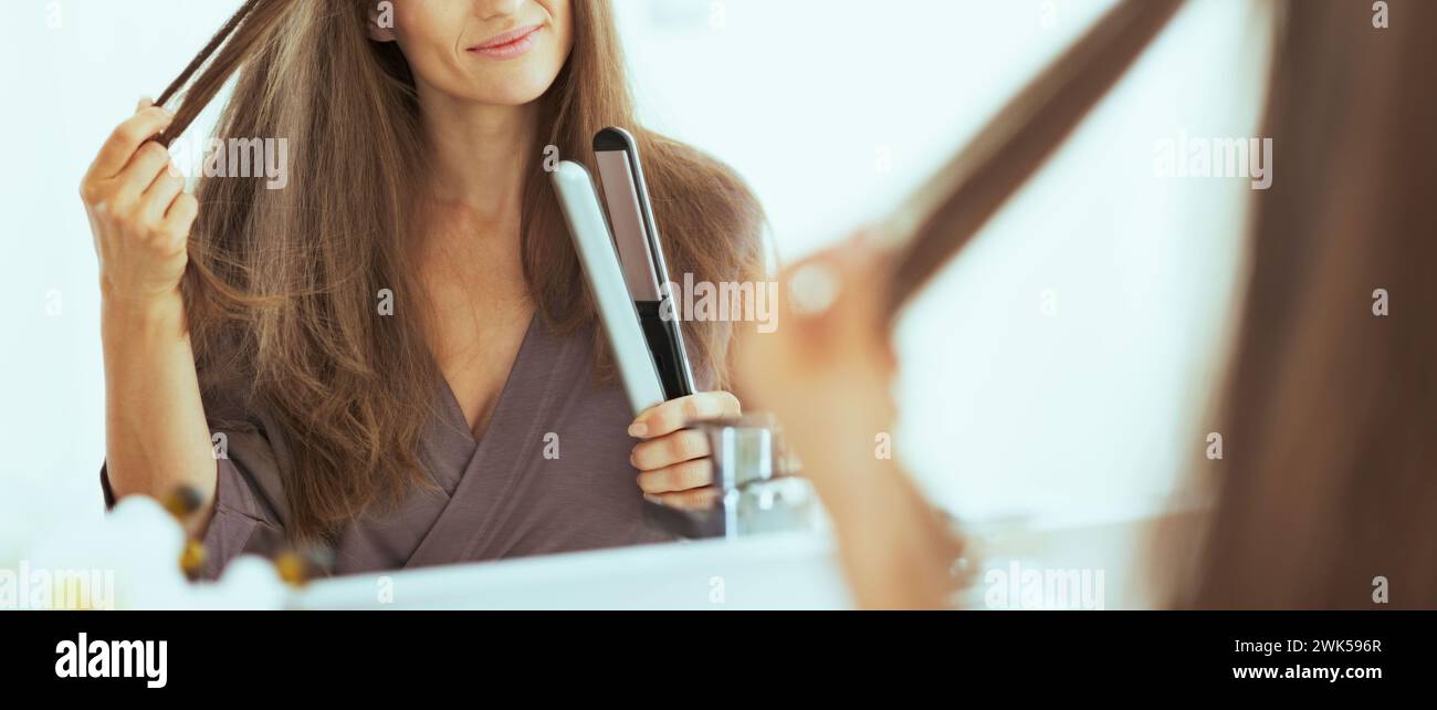 Happy young woman checking hair after straightening Stock Photo - Alamy