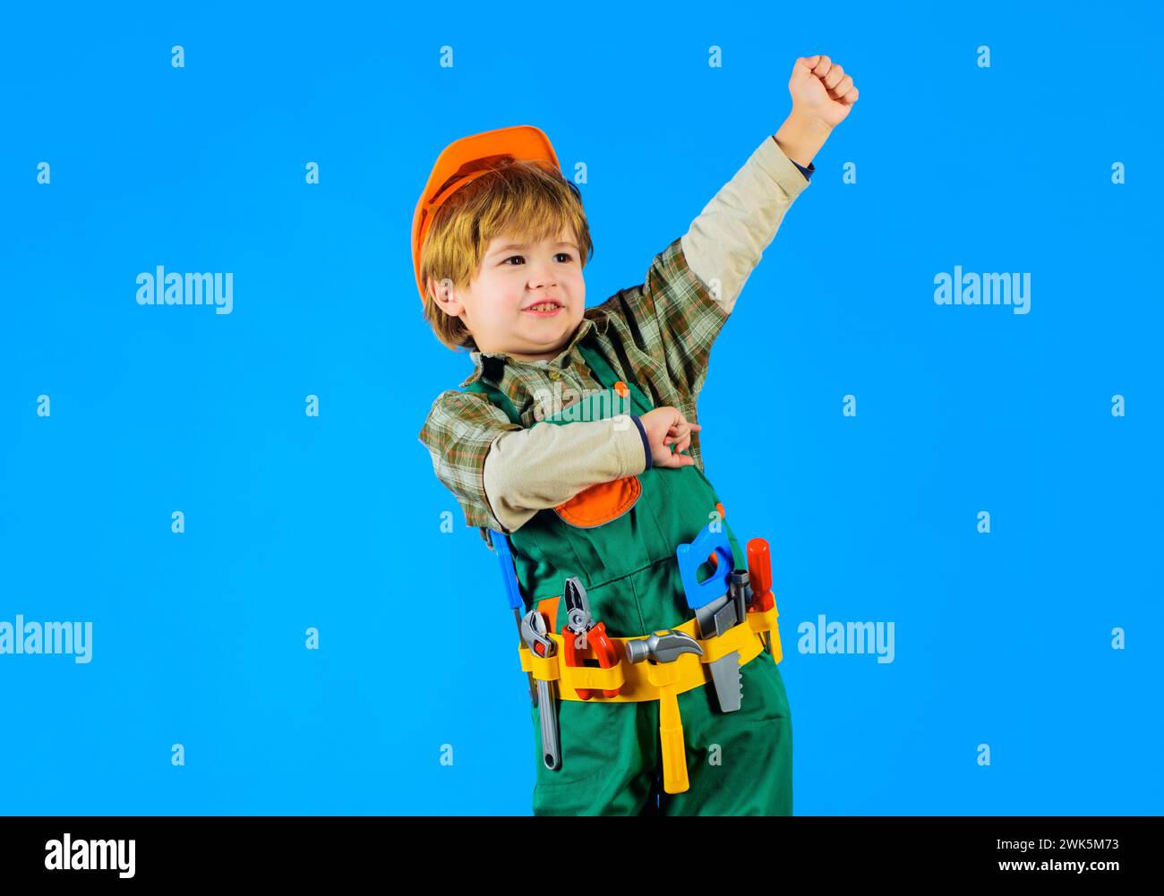 Little child in builders uniform and hard hat with toy tools. Kid playing with repair tools. Cute boy with toolbelt of tools for building. Kid Stock Photo