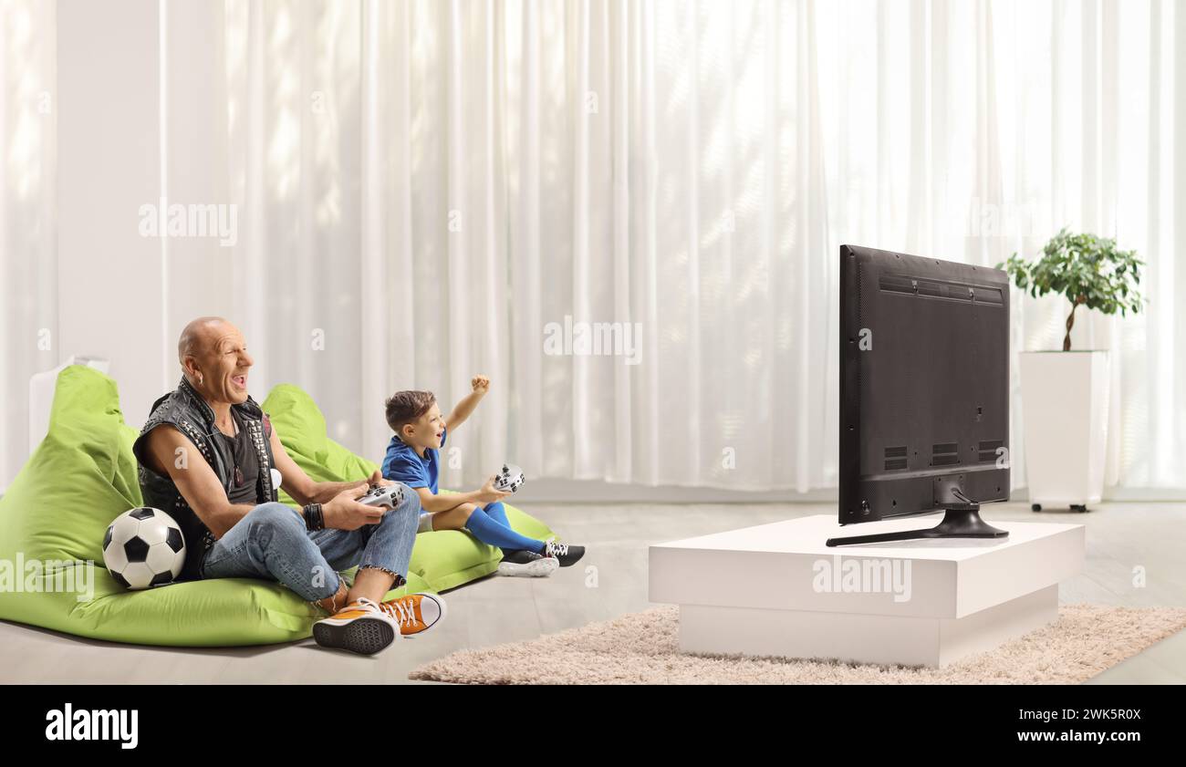 Мan playing football video game with a happy kid in front of a tv at home Stock Photo