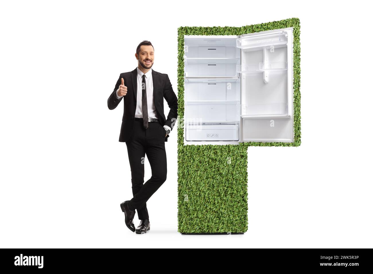 Full length portrait of a salesman with a green eco friendly fridge gesturing thumbs up isolated on white background Stock Photo