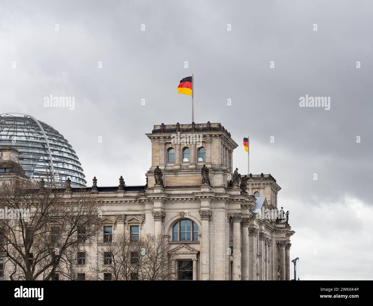 Reichstag building exterior with the German flag on the rooftop. The historical governmental house is a travel destination. The dark sky is dramatic. Stock Photo
