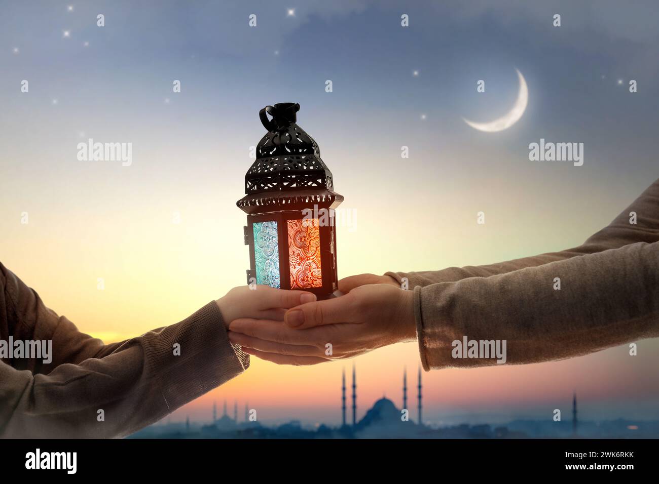 Ornamental Arabic lantern with burning candle glowing in hand. Festive greeting card, invitation for Muslim holy month Ramadan Kareem. Stock Photo