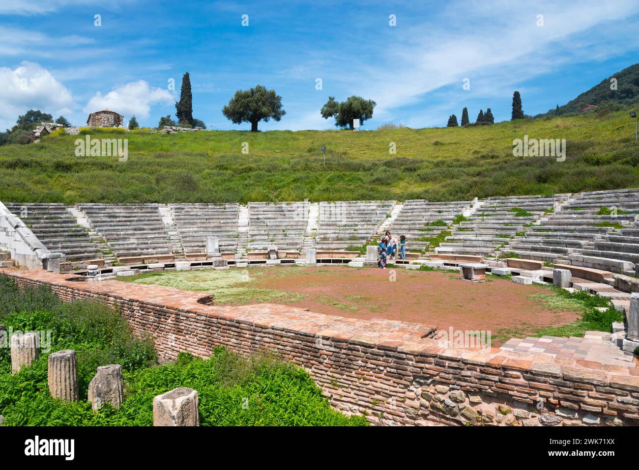 An ancient amphitheatre with surrounding green landscape and hills under a partly cloudy sky, Messene, ancient Greek polis, Messini, Messinia Stock Photo