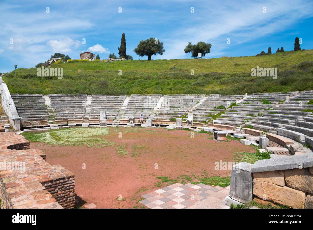 Ancient amphitheatre with numerous seating steps, surrounded by grass, under a wide blue sky, Messene, ancient Greek polis, Messini, Messenia Stock Photo