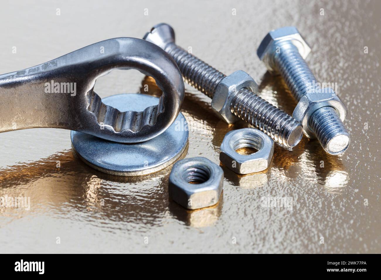 Ring wrench, nuts and bolts on golden metal surface close up Stock Photo