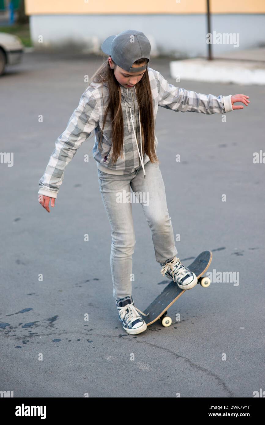 child girl outdoors studying skateboard tricks Stock Photo
