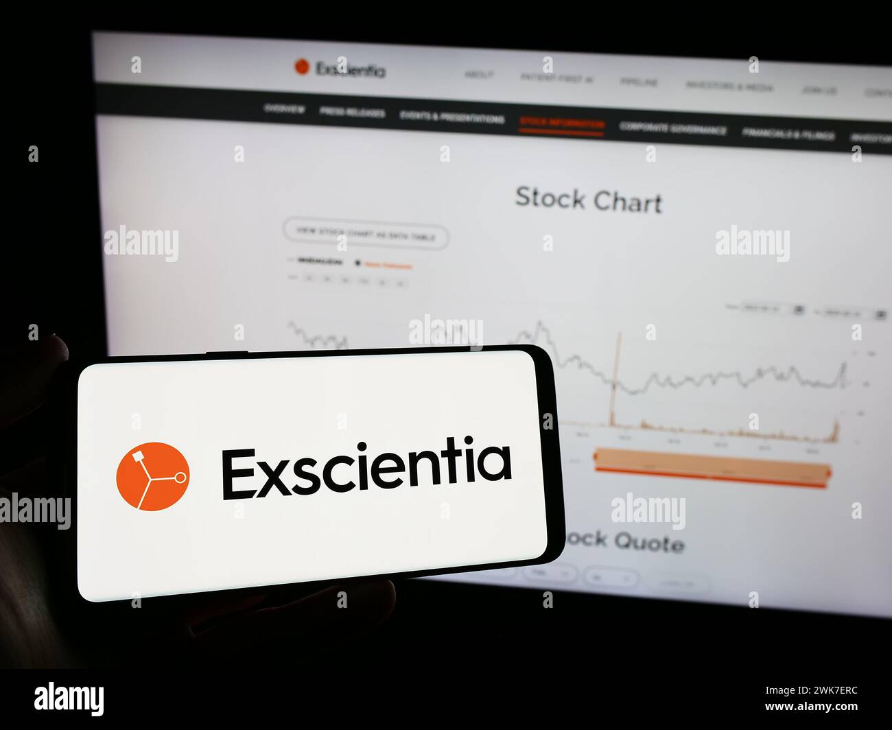 Person holding mobile phone with logo of British artificial intelligence company Exscientia plc in front of web page. Focus on phone display. Stock Photo