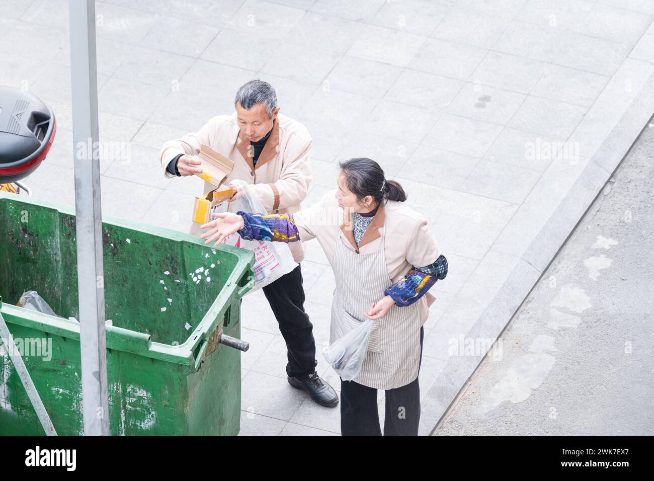 Old man and woman taking out trash Stock Photo