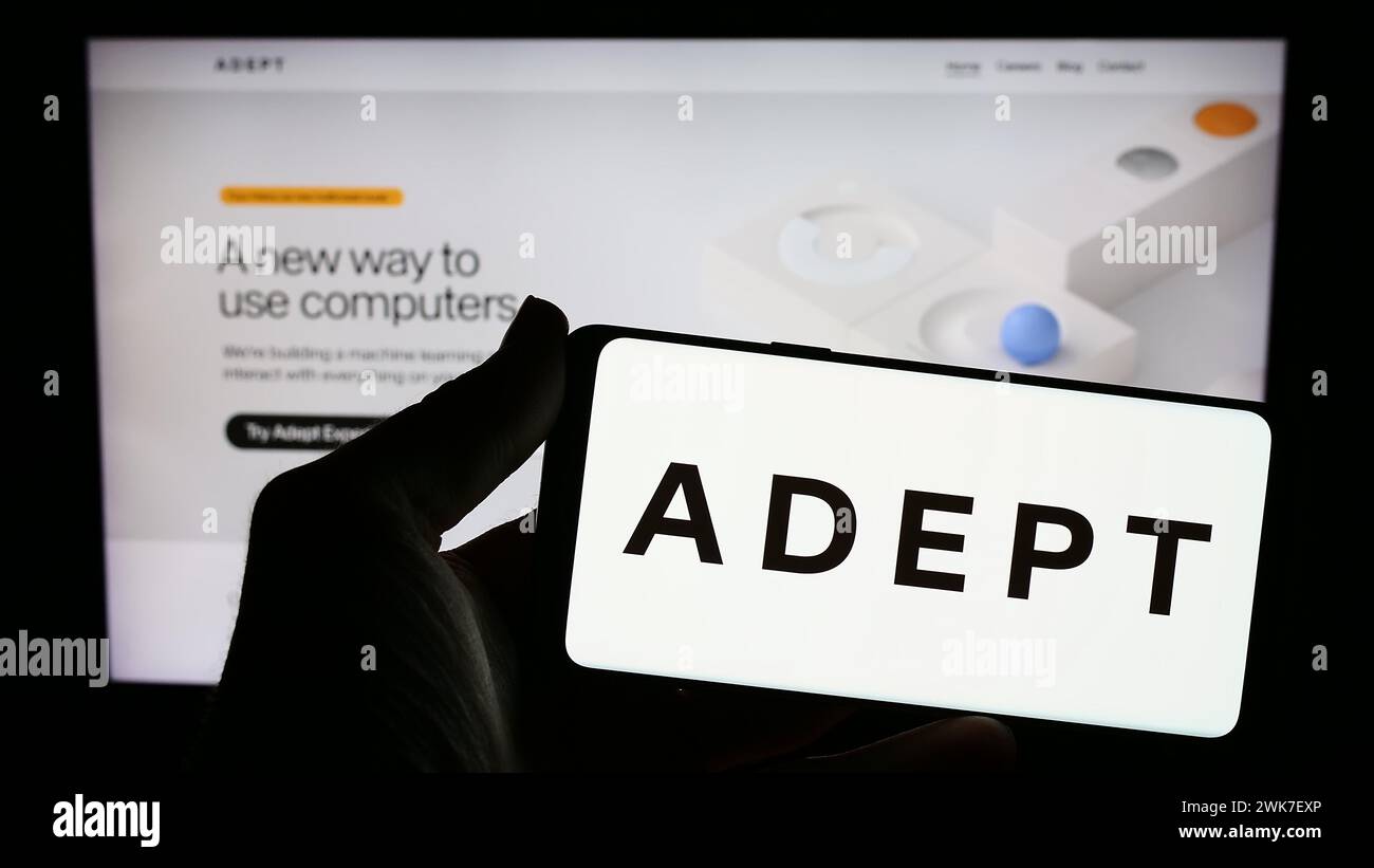 Person holding smartphone with logo of US artificial intelligence research company Adept AI in front of website. Focus on phone display. Stock Photo