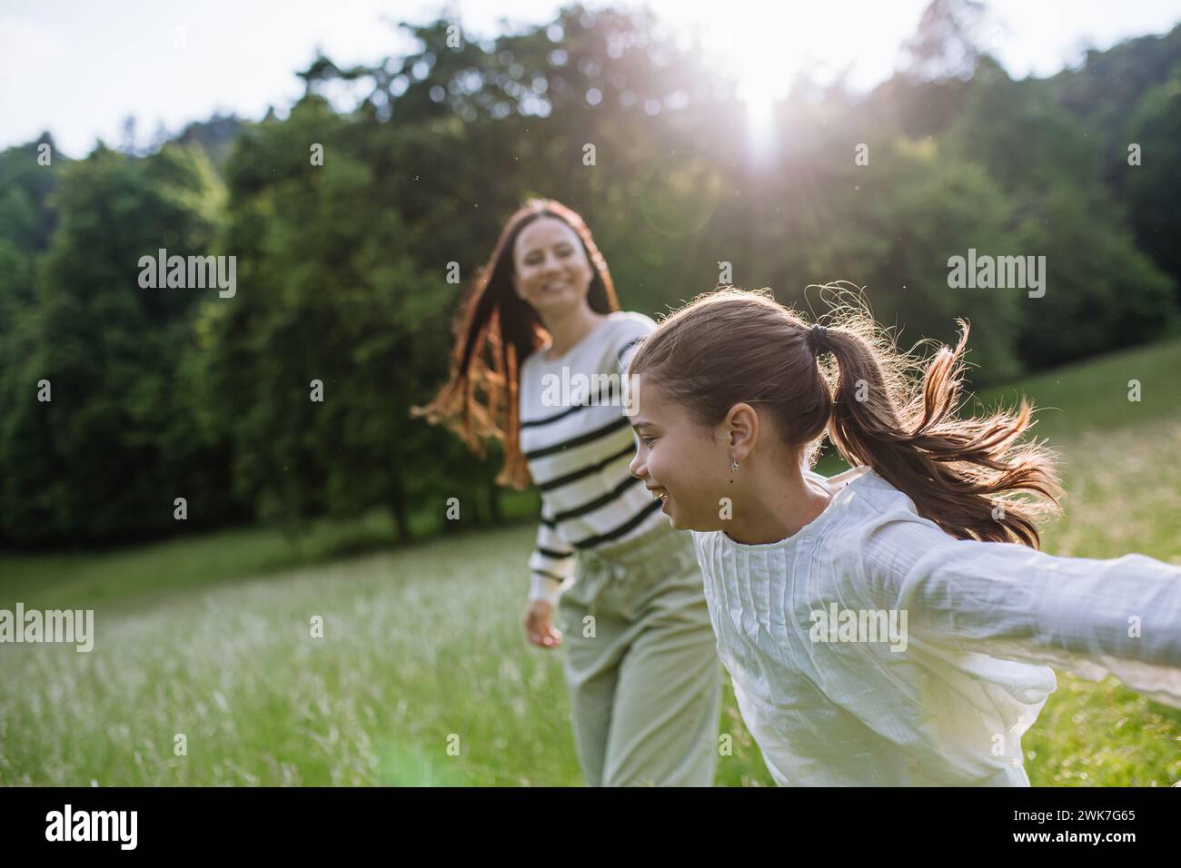 Beautiful mother with daughter, playing at meadow, running and having fun. Concept of Mother's Day and maternal love. Stock Photo