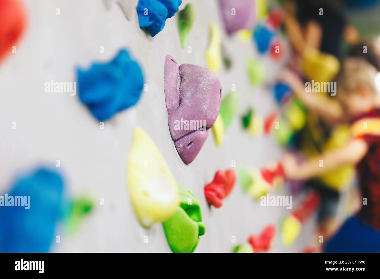 Bouldering Climbing Wall Holds Kids Playing in Background. Indoor Climbing Equipment Stock Photo