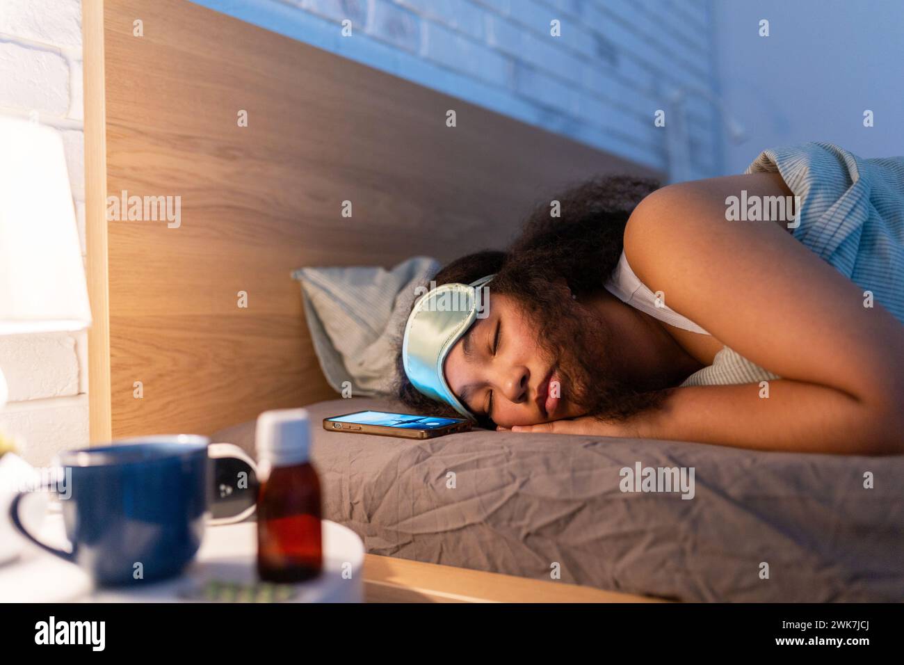 Woman sleeping with sleep mask, using sleeping pills, melatonin. Concept of sleep routine. Insomnia a sleep problems among adults. Stock Photo