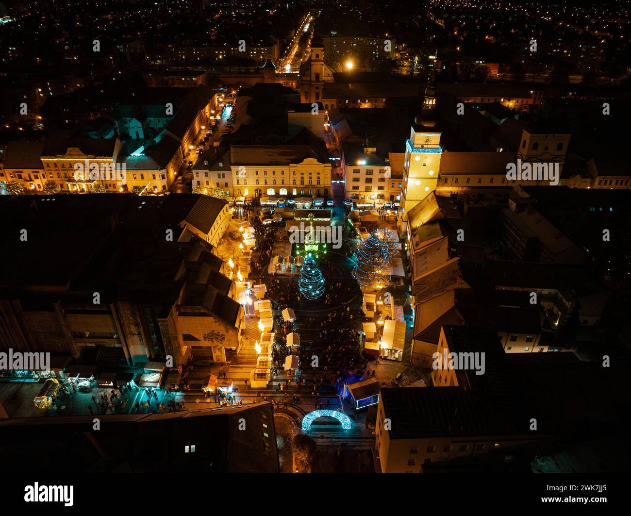 Aerial night shot of city during Christmas, winter and christmas decorations on city square. Chistmas market during holiday season in small city. Stock Photo
