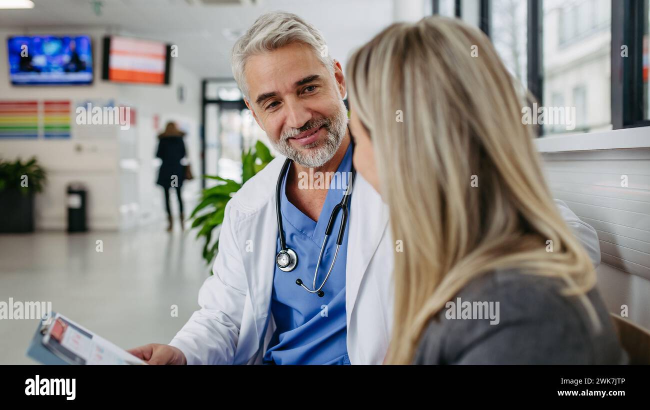 Pharmaceutical sales representative talking with doctor in modern clinic. Ambitious female medical rep presenting new medication. Female hospital dire Stock Photo