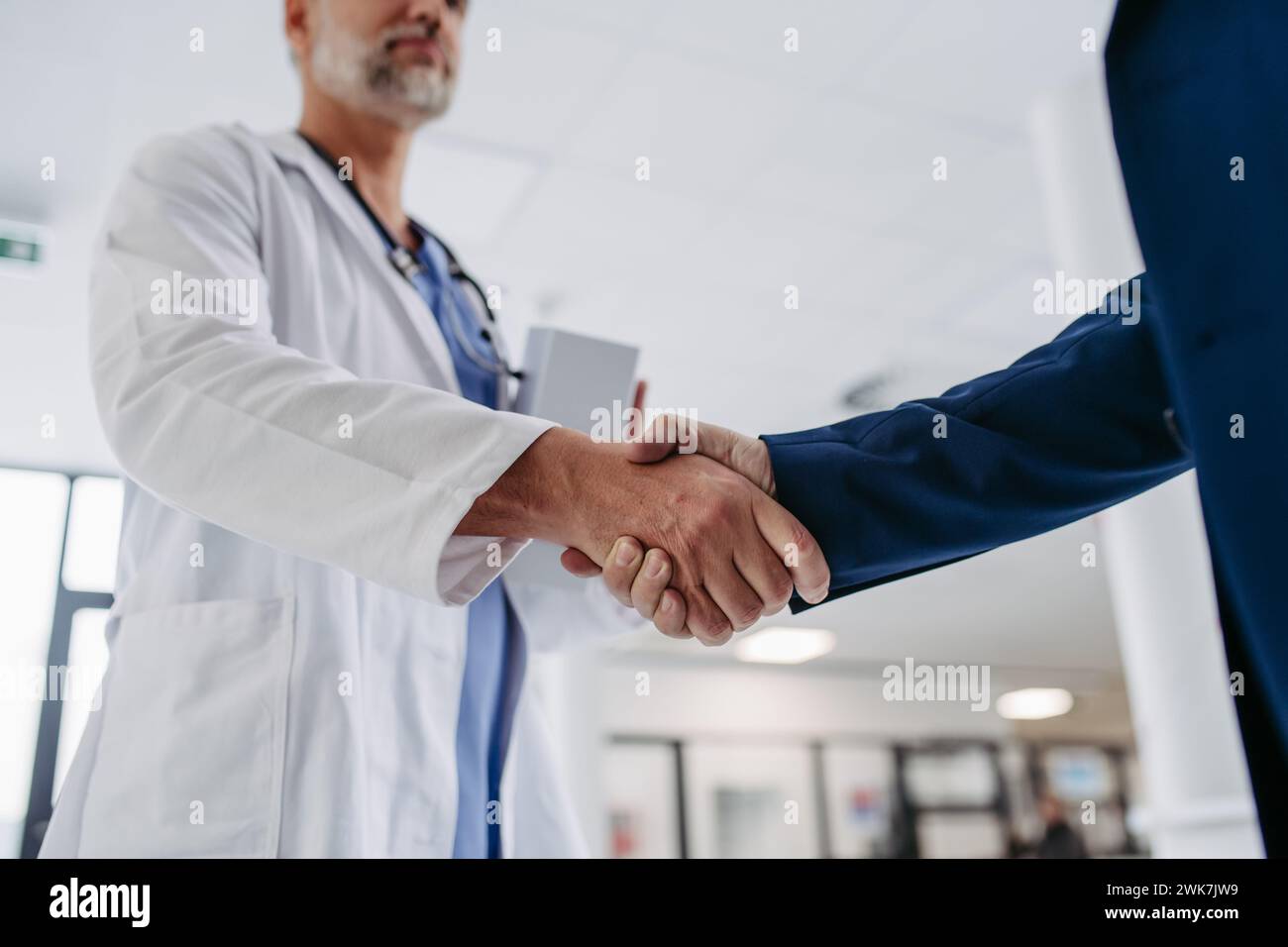 Close up of pharmaceutical sales representative standing in doctor office, shaking hands. Hospital director, manager of private medical clinic greetin Stock Photo