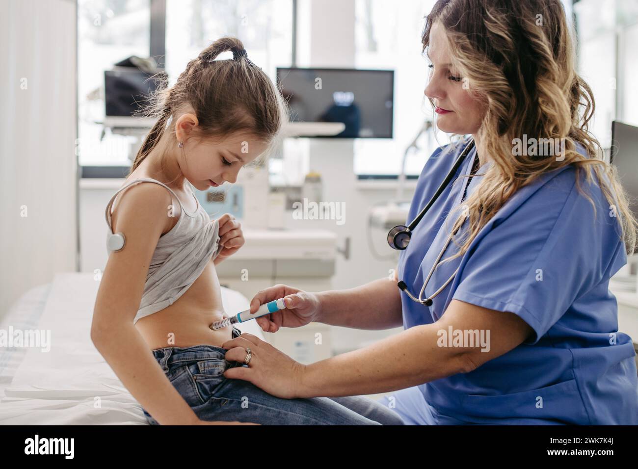 Nurse injecting insulin in diabetic young girl belly. Close up of young girl with type 1 diabetes taking insuling with syringe needle. Stock Photo