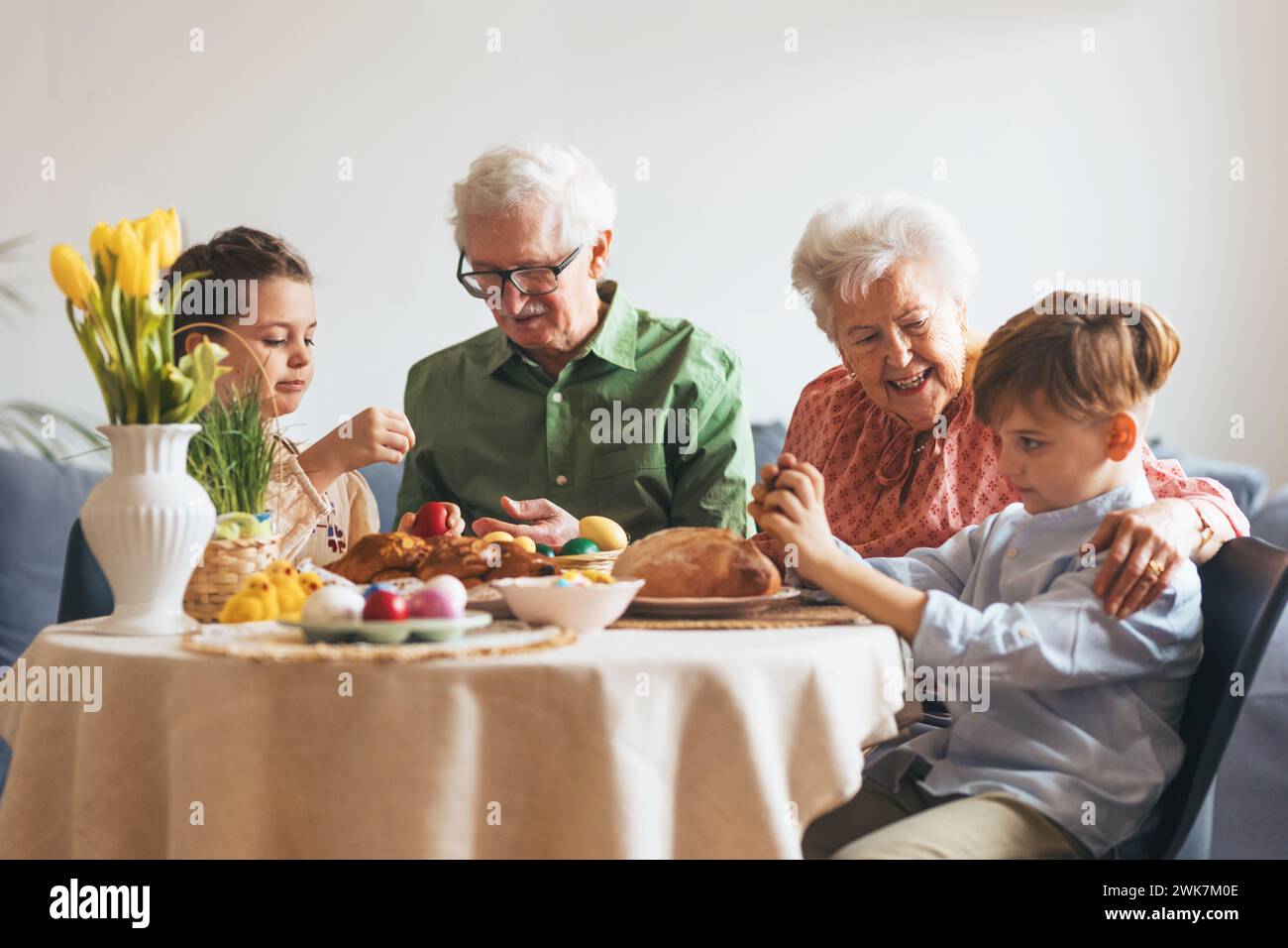 Grandparents with grandchildren eating traditional easter lunch. Recreating family traditions and customs. Happy easter. Stock Photo