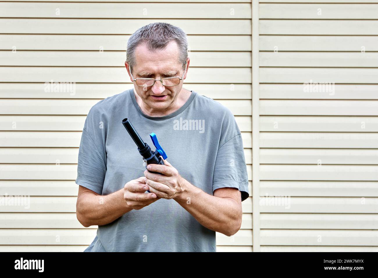 Middle aged man installs drinking water connection pipeline using valve fitting with compression connection. Stock Photo