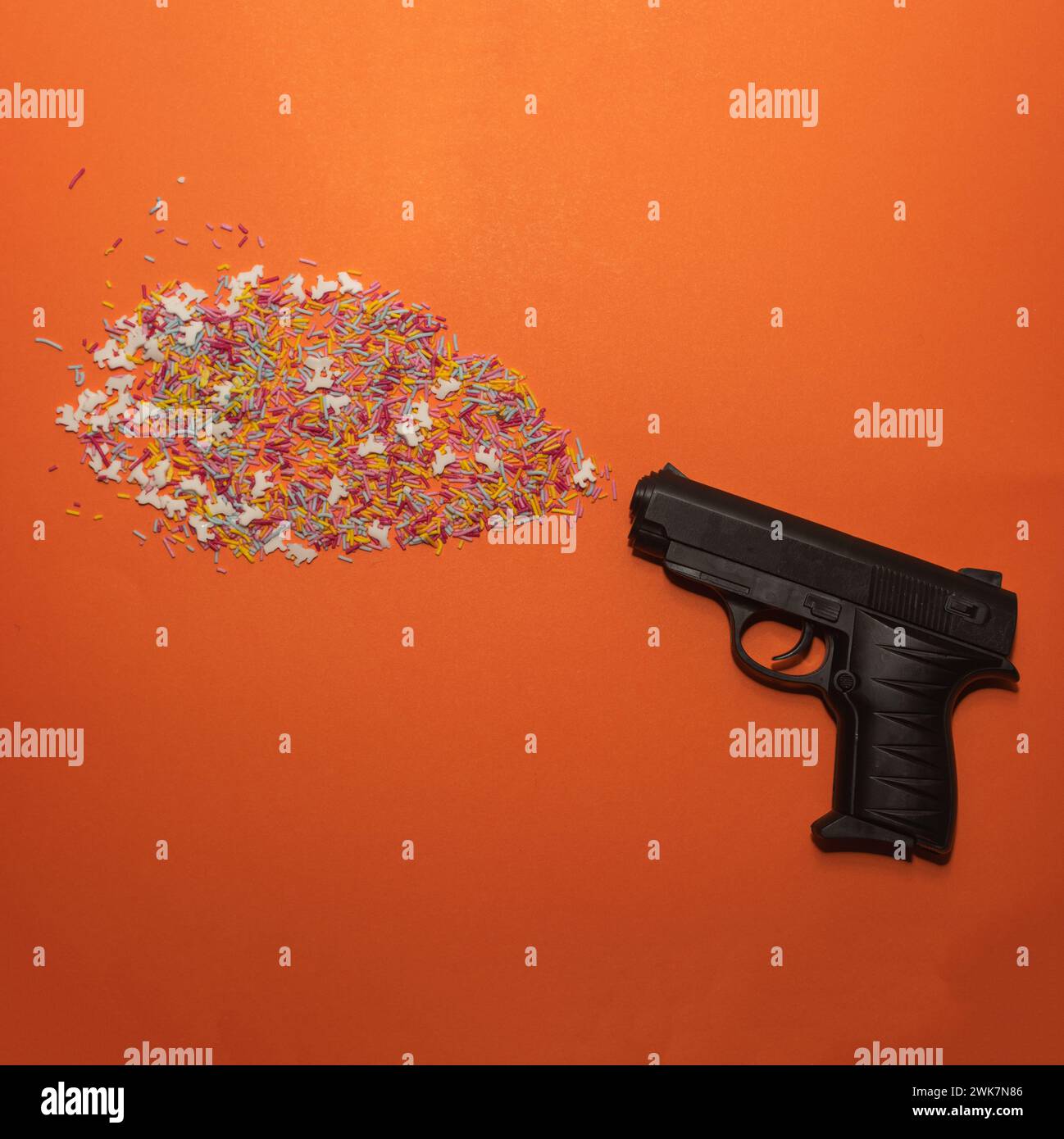 Pistol shooting sprinkles creative concept. Flat lay. Stock Photo