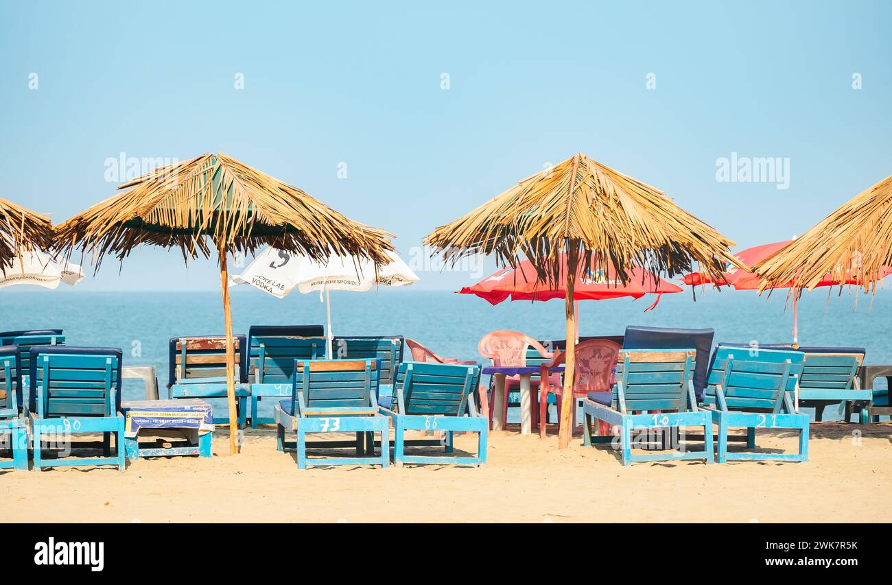 Empty Chairs Under Thatched Umbrellas On A Sandy Beach In Goa India