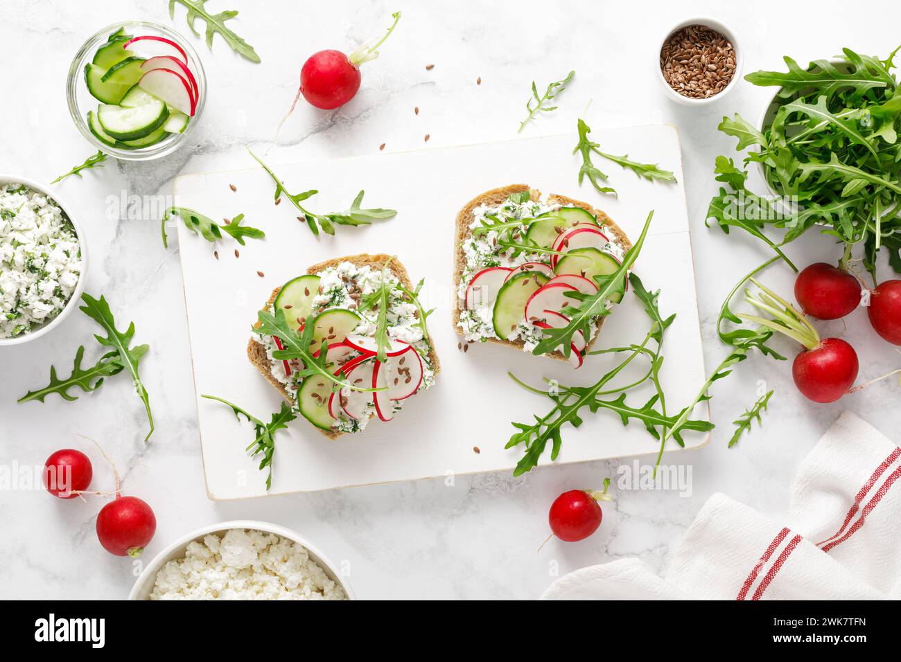 Sandwiches with rye bread toasts, cottage cheese, radish, cucumber, fresh greens and arugula for a healthy breakfast, top view Stock Photo
