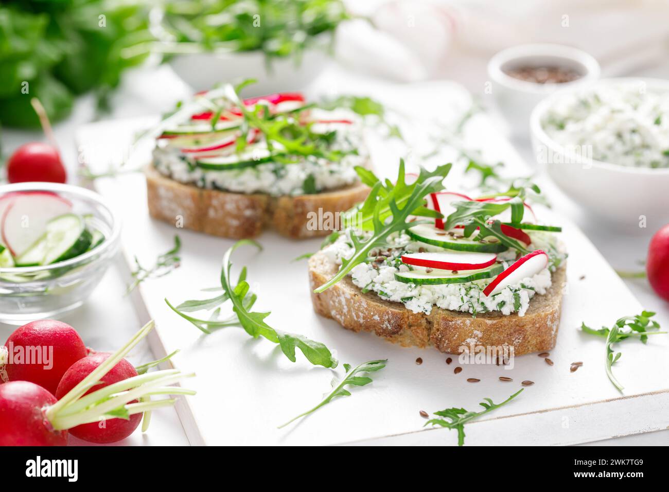 Sandwiches with rye bread toasts, cottage cheese, radish, cucumber, fresh greens and arugula for a healthy breakfast Stock Photo