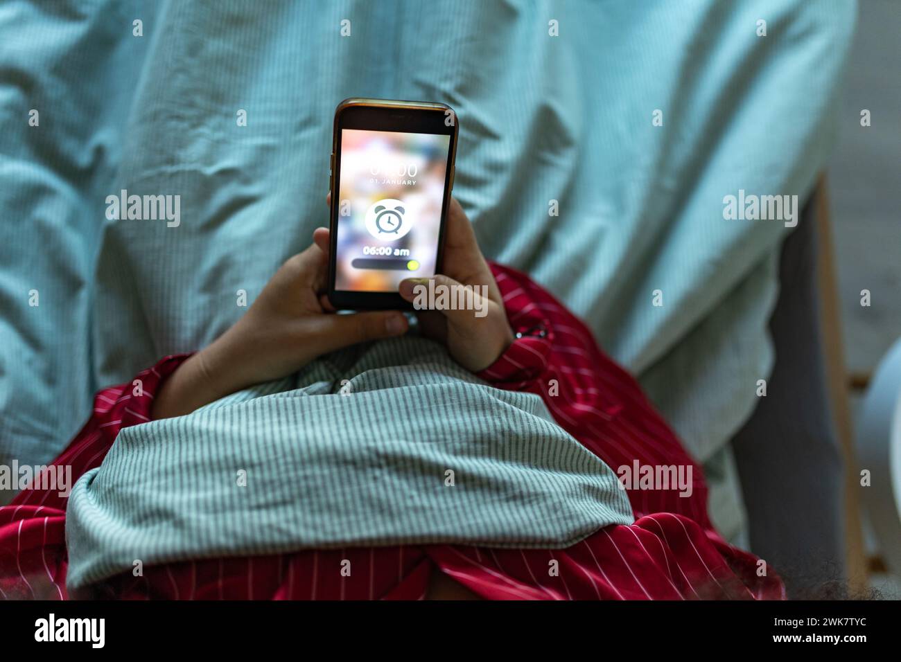 Woman setting alarm before going to sleep. Concept of sleep routine. Insomnia a sleep problems among adults. Stock Photo