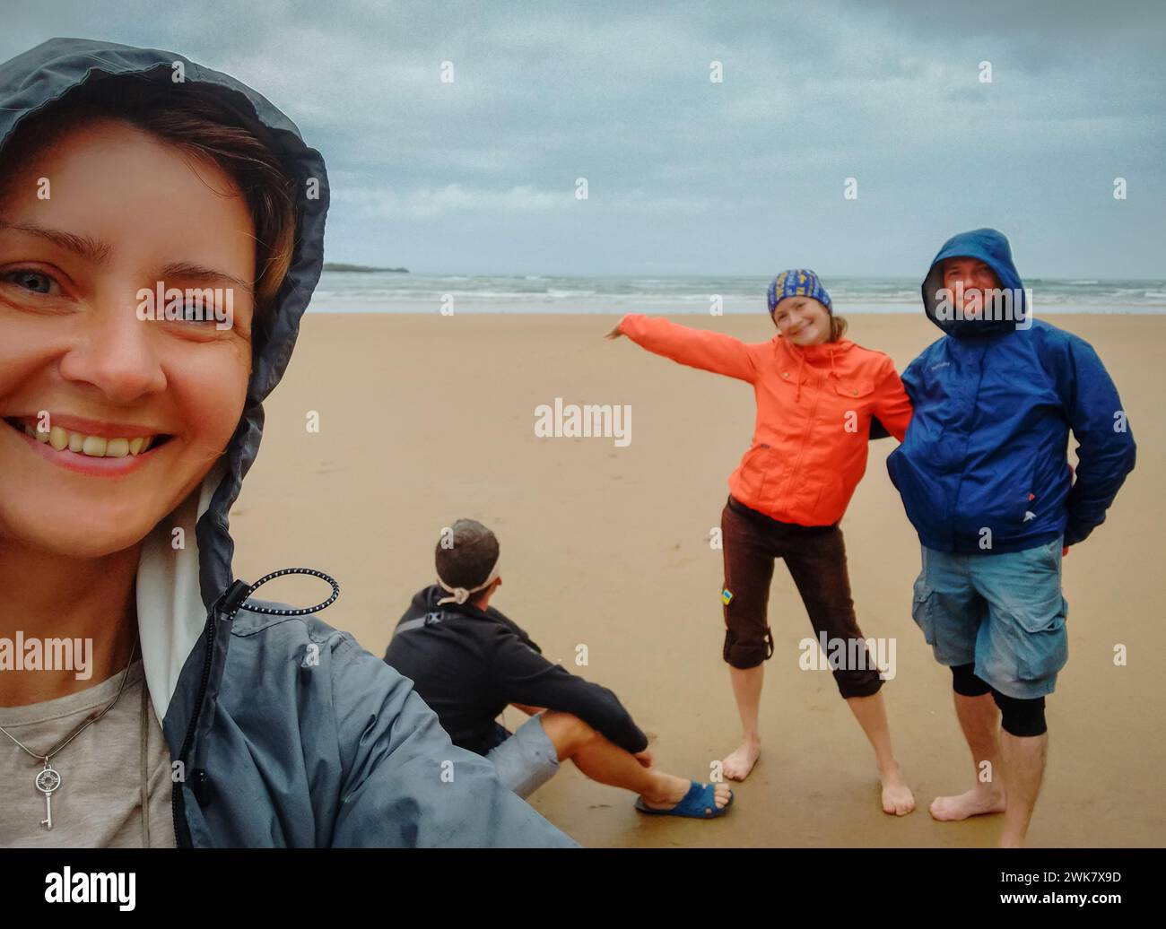 Four happy people on the beach. Pilgrims on Camino de Santiago. Family time. Tourists on coast. Amazing moment together. Friendship time. Stock Photo