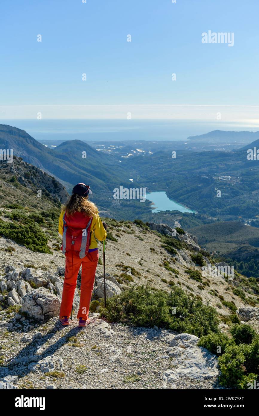 A woman standing on a rocky point overlooking Mediterranean sea, Malla del Llop peak, Alicante, Costa Blanca, Spain - stock photo Stock Photo