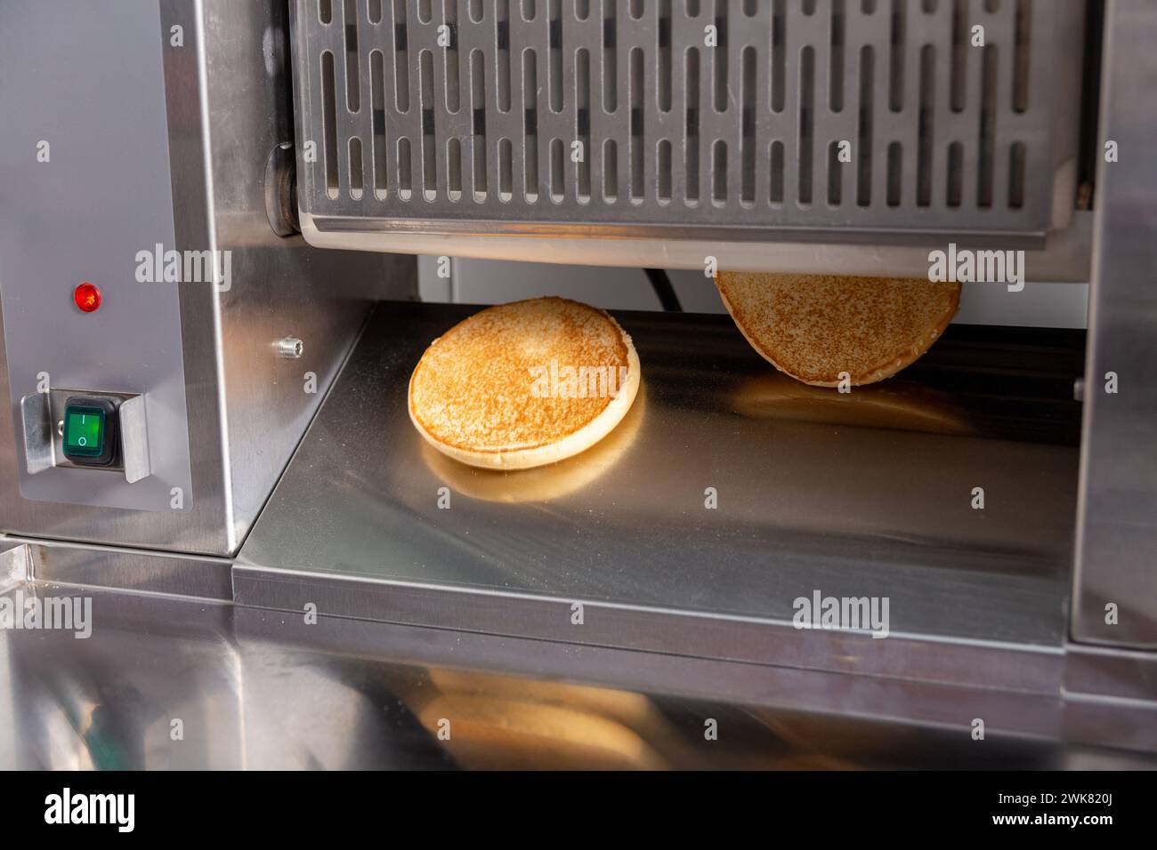 Conveyor toaster for frying burger buns to a crisp. The cook puts the