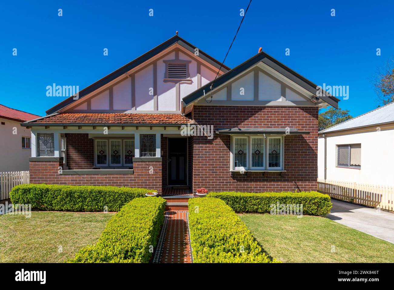 An asymmetrical Californian Bungalow home from the 1920's fronted by a very symmetrical hedge and garden in Gladesville, Sydney, Australia Stock Photo