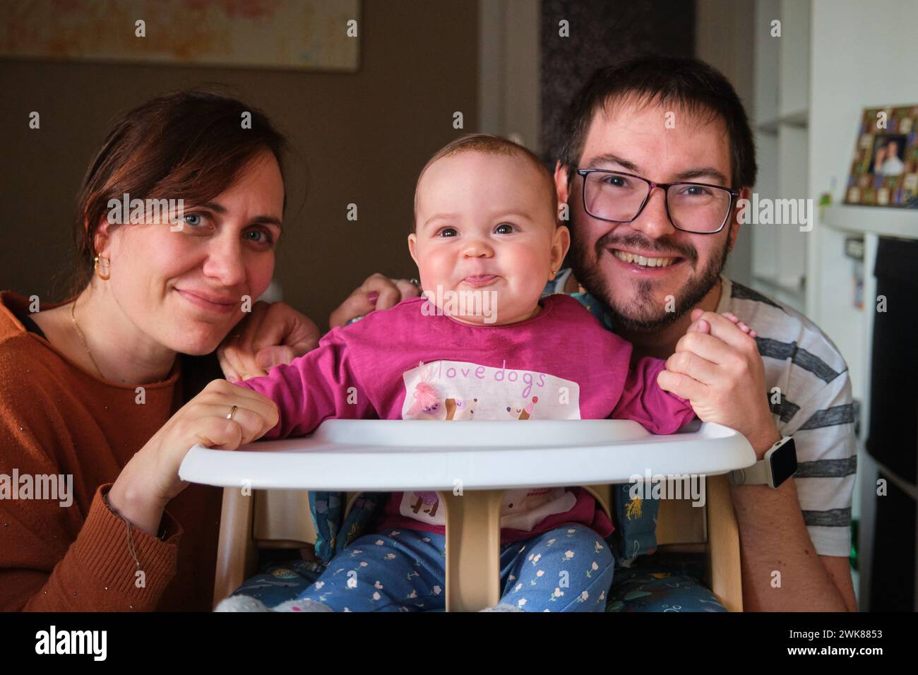 Parents smiling and their 6MonthOld baby girl blowing raspberries