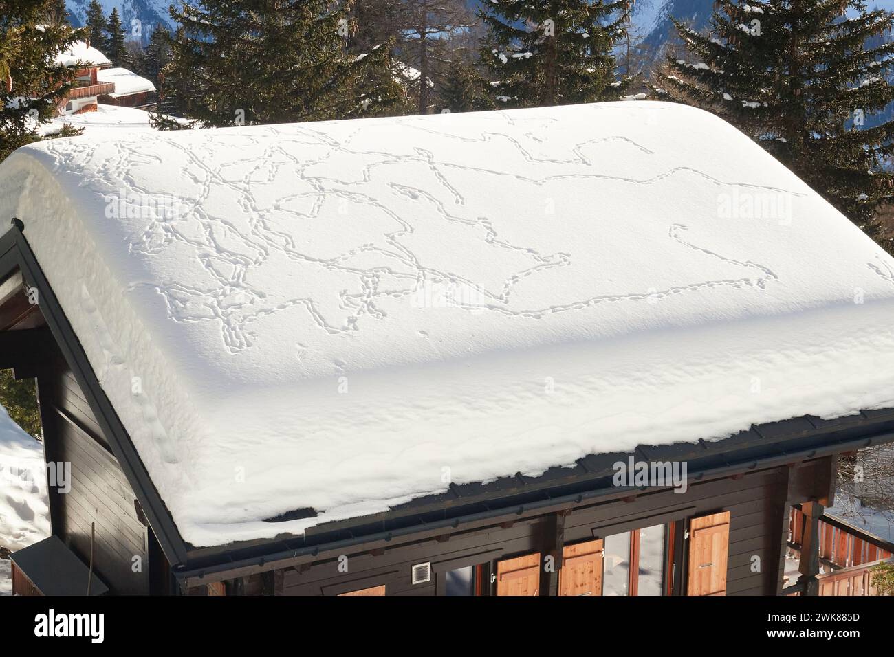 A snow-covered roof of a rural cottage with foot tracks. Bettmeralp, Switzerland Stock Photo