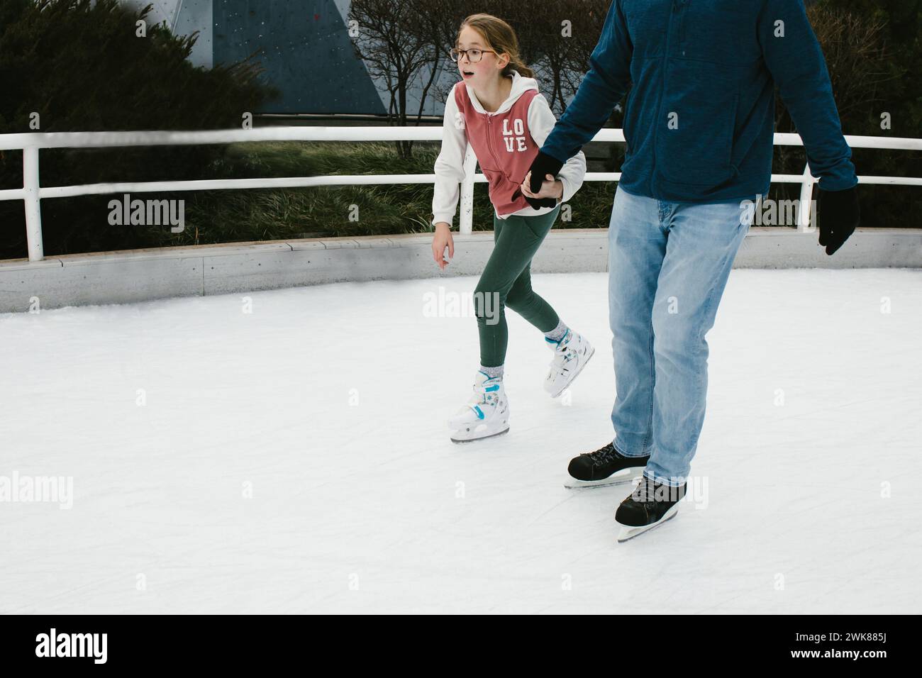 Daughter holds Dads hand while they ice skate together Stock Photo