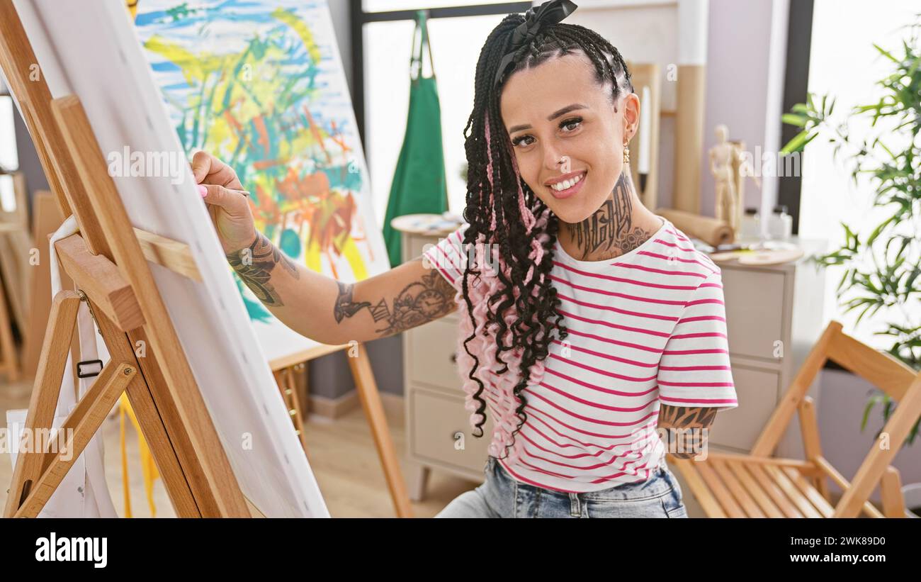 Confident amputee artist, joyful hispanic woman perfects drawing skill in the studio, embracing handicapped creativity with a smile Stock Photo